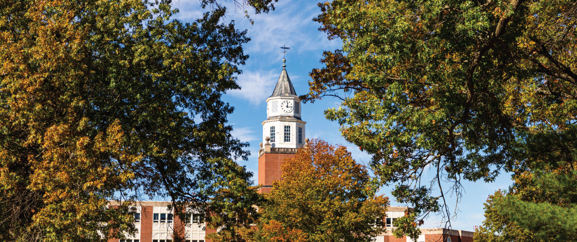 Photo of the Pulliam Clocktower centered between two large trees